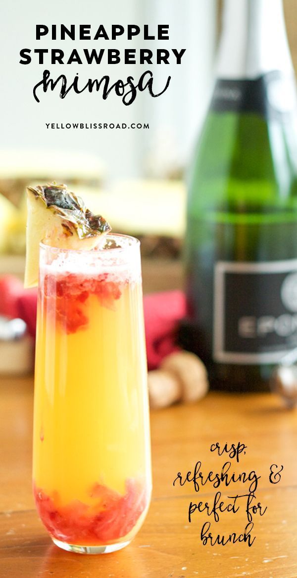 a pineapple and raspberry punch in a glass with a bottle behind it