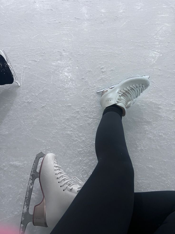 two people are sitting on the ice with their feet in the snow and one is wearing white shoes