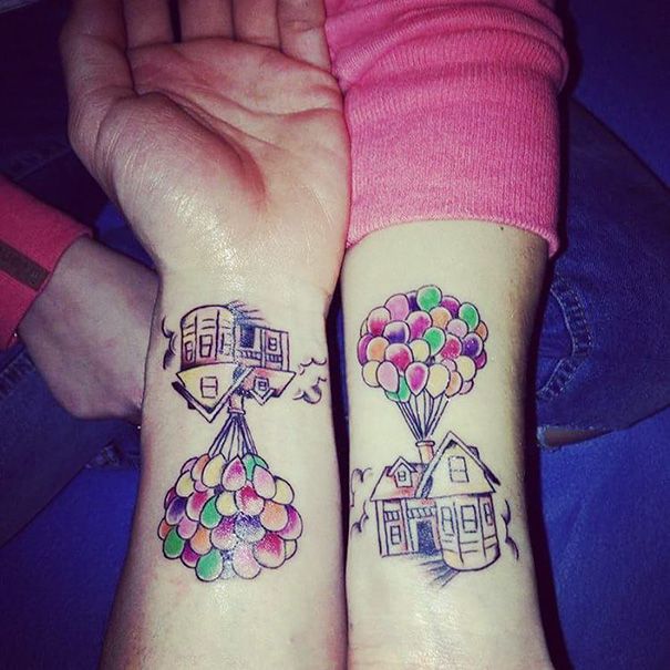 two people with tattoos on their arms holding hands and balloons in the shape of houses