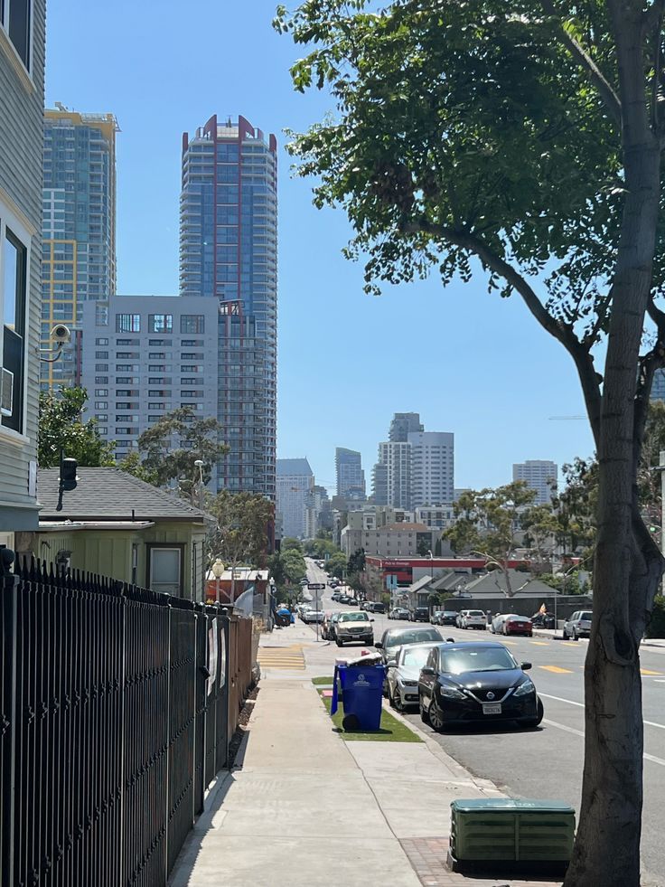 cars parked on the side of a street in front of tall buildings and skyscrapers