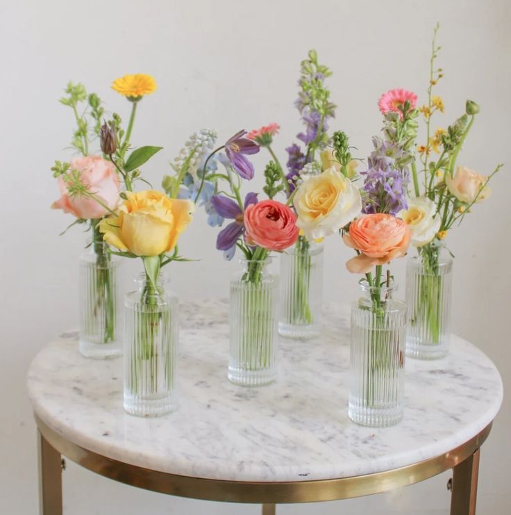 five vases with flowers are sitting on a marble table