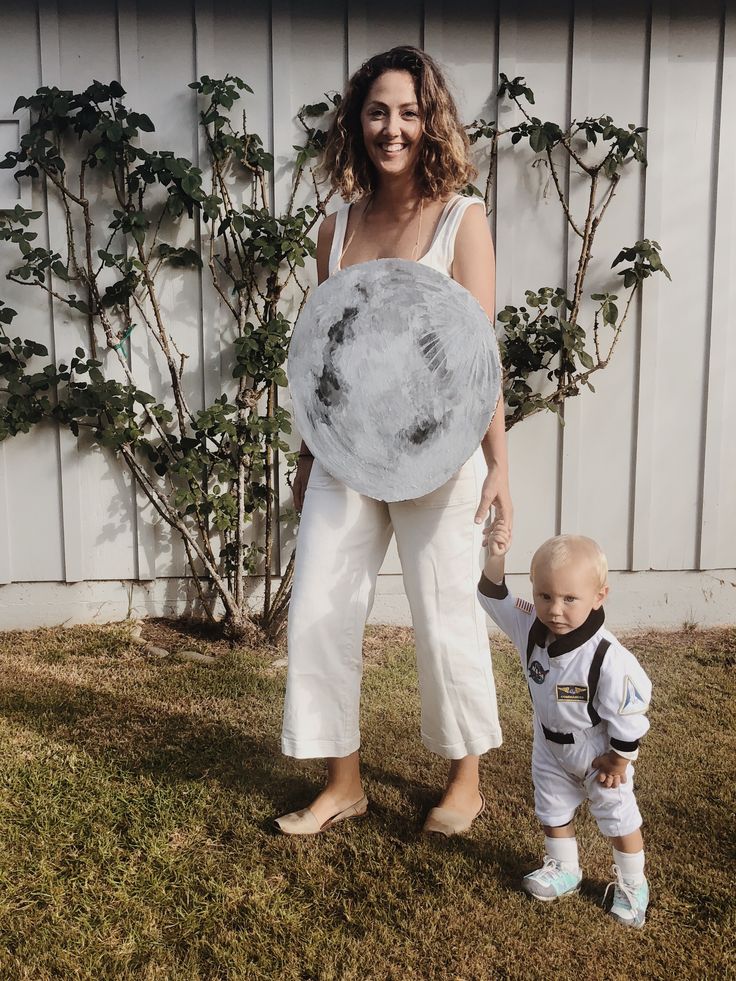 a woman in white pants and a baby holding an object with the moon on it