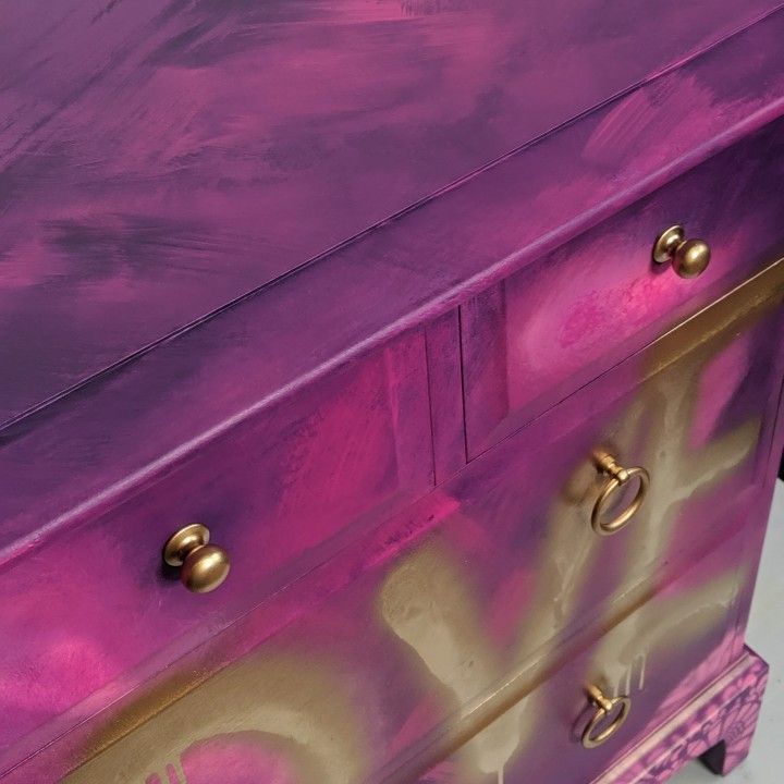 a purple and gold painted chest of drawers