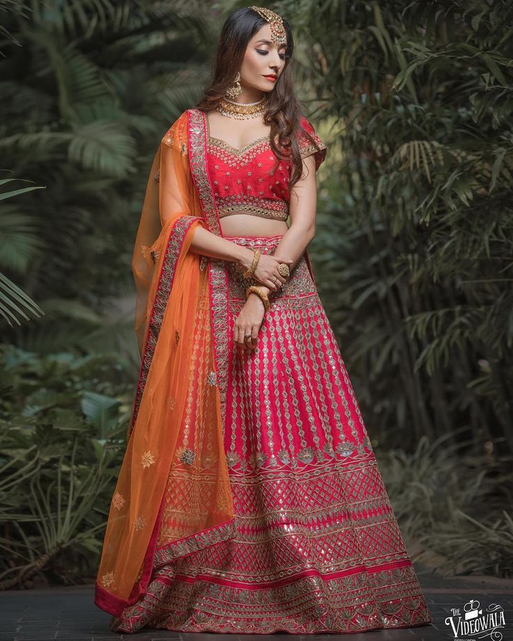 a woman in a red and orange lehenga