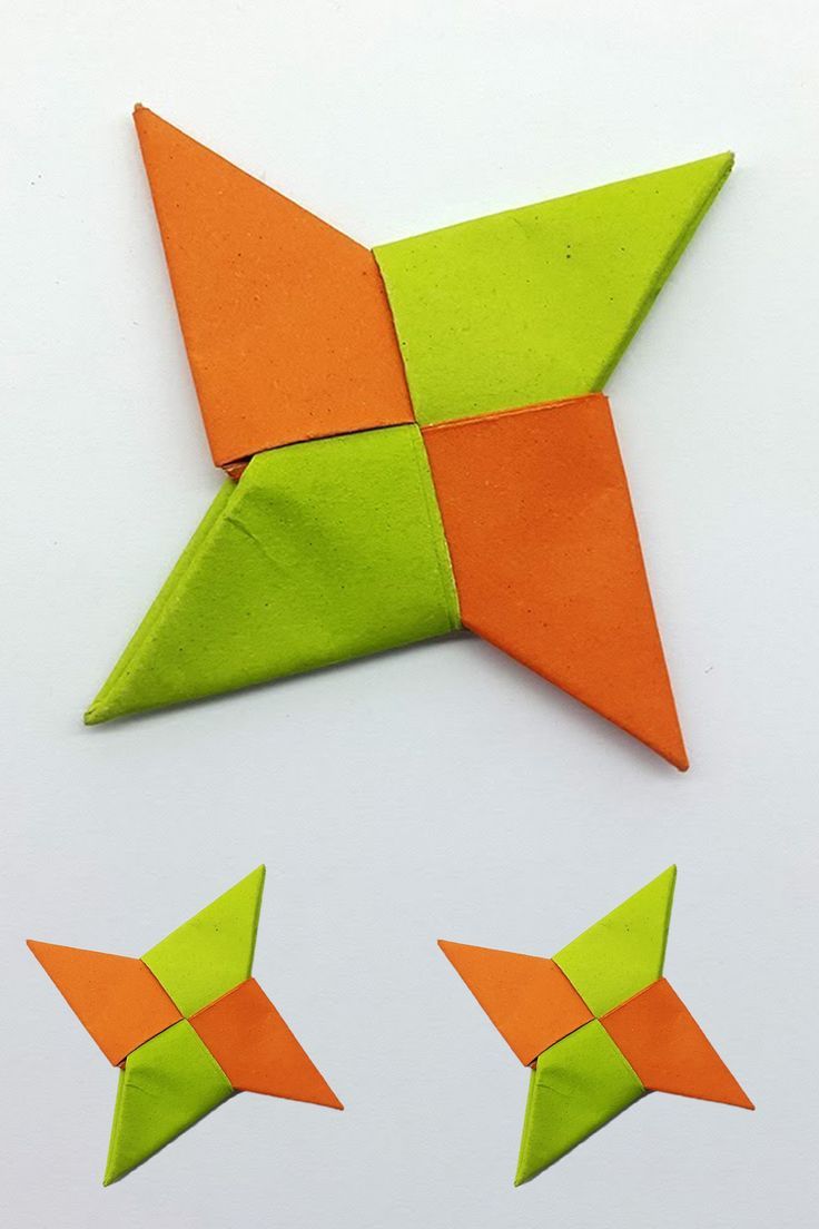 an orange and green origami star next to three smaller ones on a white surface