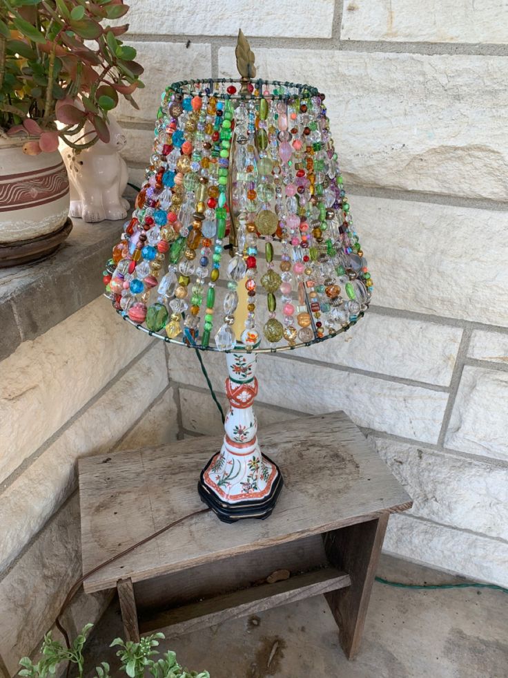 a lamp made out of glass bottles on top of a table next to a potted plant