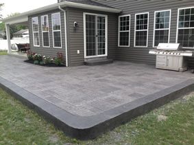 a backyard with a concrete patio surrounded by grass