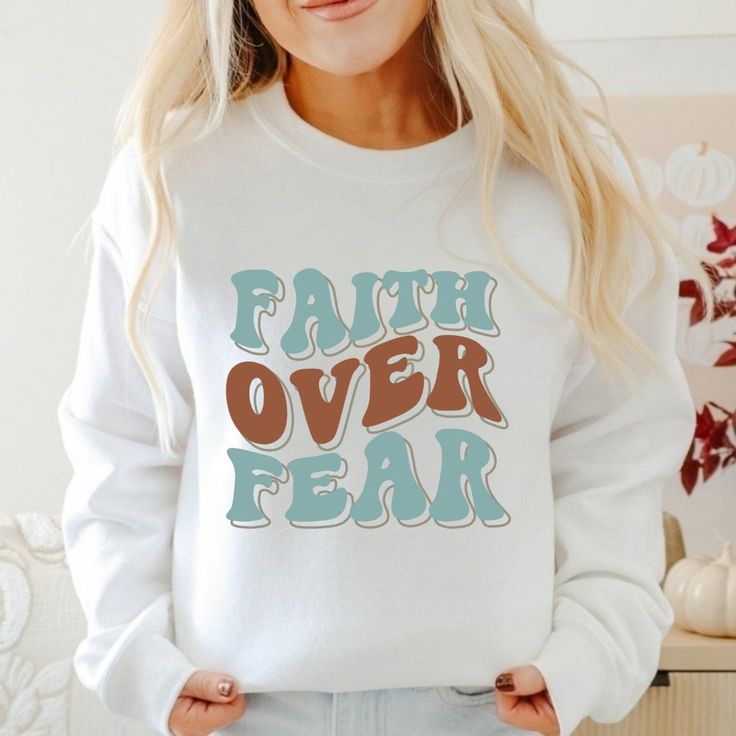 Embrace strength and faith with our 'Faith Over Fear' faith-based sweatshirt, a powerful reminder of courage and resilience in challenging times. Crafted from premium materials, this sweatshirt offers both comfort and style, featuring a timeless design that speaks volumes. Whether you're running errands or cozying up at home, let this sweatshirt inspire confidence and trust in God's plan. Perfect for gifting or personal wear, it's a meaningful addition to any wardrobe. Embody the message of fait Inspirational Text Print Sweatshirt For Fall, Inspirational Graphic Print Sweatshirt For Fall, Inspirational Letter Print Sweatshirt For Fall, Inspirational Graphic Print Fall Sweatshirt, Fall Inspirational Graphic Print Sweatshirt, Inspirational Text Print Fall Sweatshirt, Inspirational Streetwear Tops For Fall, Inspirational Slogan Sweatshirt For Fall, Challenging Times