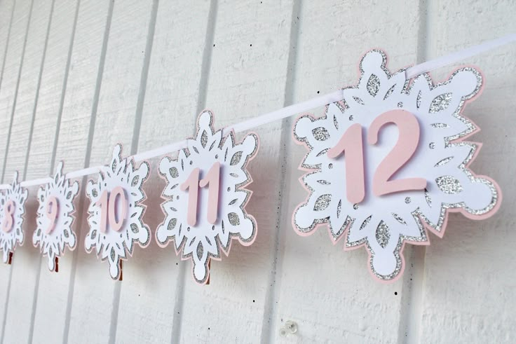 some paper snowflakes are hanging from a line with numbers on it and one number is 12