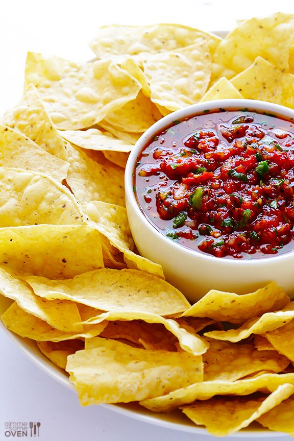 a white bowl filled with salsa surrounded by tortilla chips