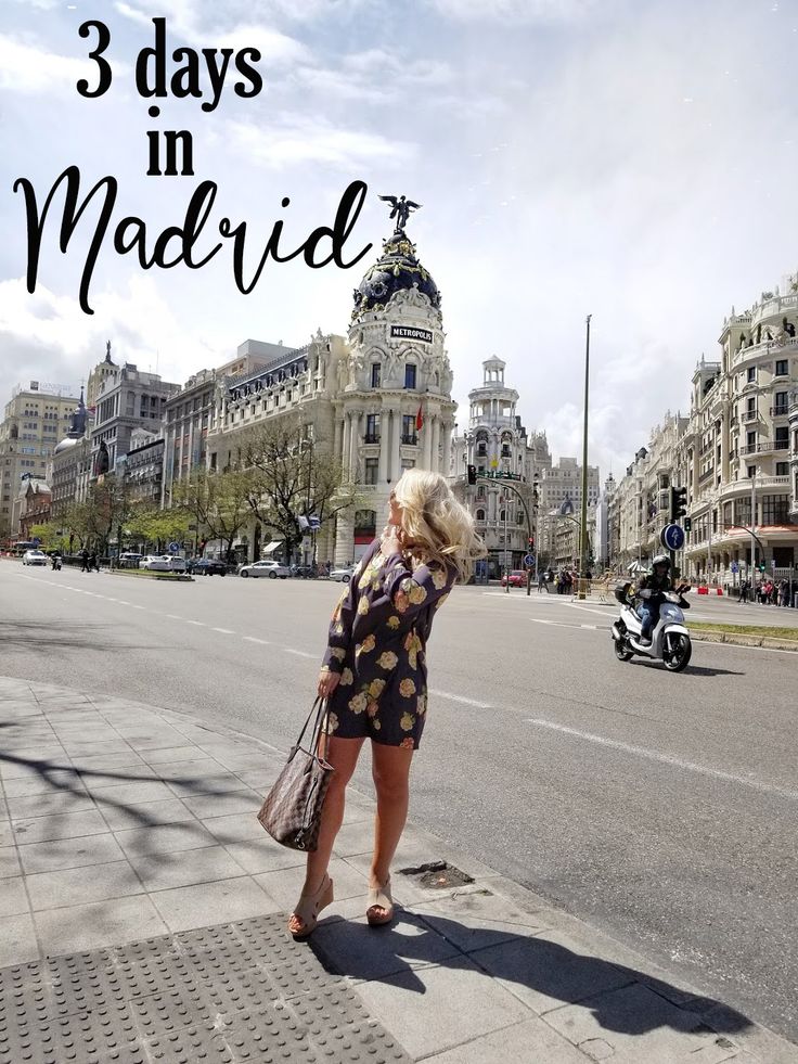 a woman is standing on the sidewalk in front of some buildings