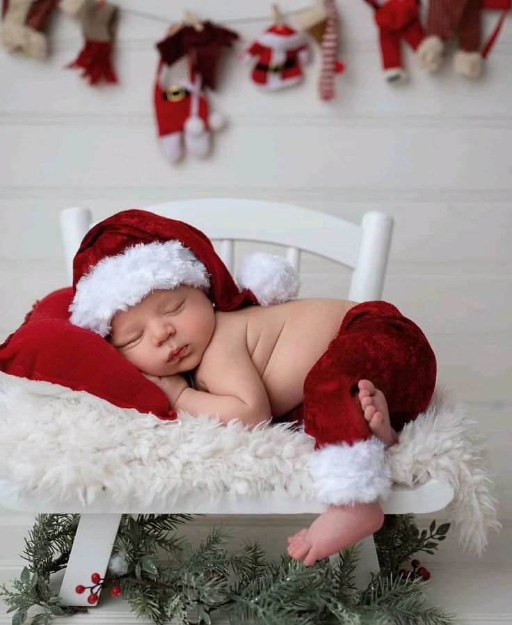 a baby wearing a santa hat sleeping on a white chair