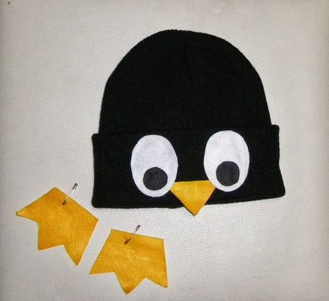 a black hat with two yellow pieces of paper cut out to look like a penguin