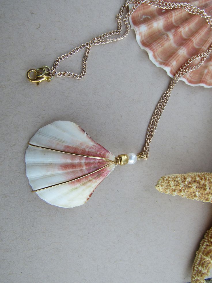 this seashell necklace is a lovely statement piece or pairs well with any of the pieces in our Gadgets and Gizmos collection Pearl Pendant Shell Gift, Pearl Pendant Shell As Gift, Pearl White Shell With Pearl Charm, White Shell-shaped Shell Jewelry, Pearl Shell With Pearl Charm, White Shell Jewelry Gift, Pearl White Shell-shaped Pearl Chain Jewelry, Pearl Charm Shell-shaped Jewelry, Shell Jewelry With Pearl Pendant