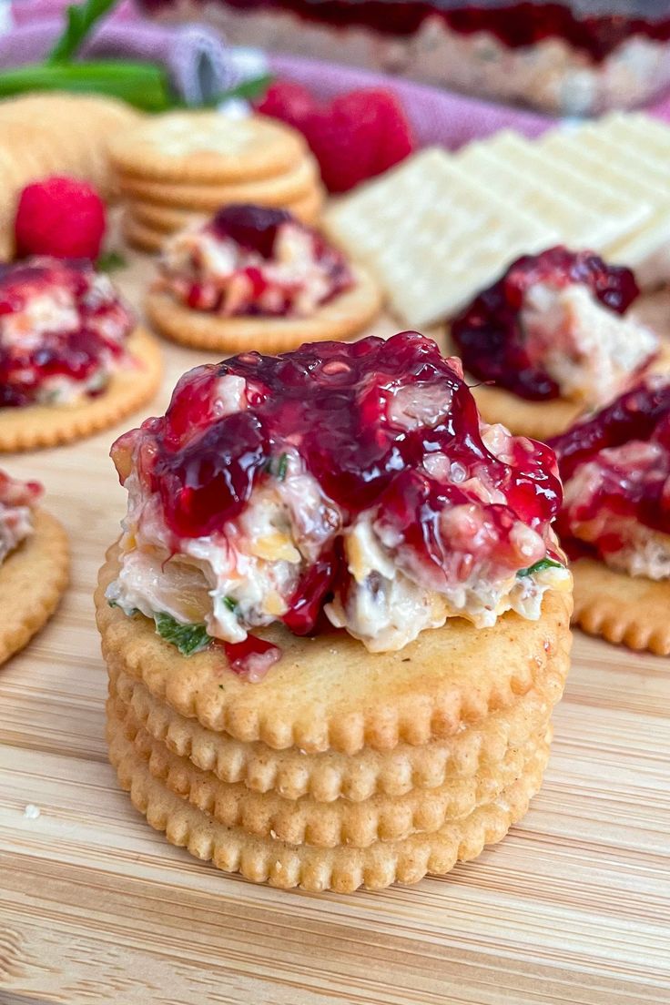 crackers topped with fruit and whipped cream on a cutting board next to other desserts