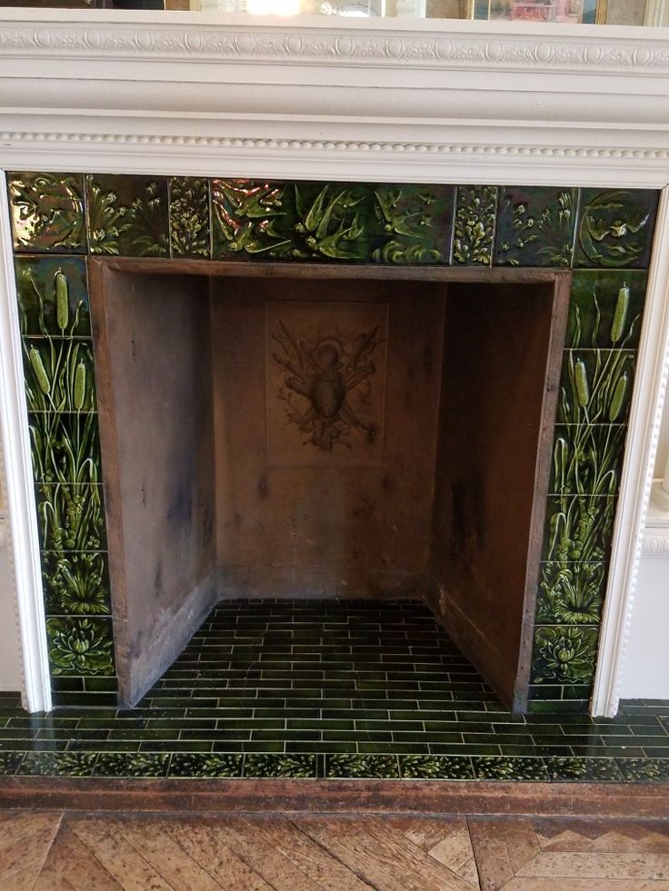 an old fireplace with green tiles on it