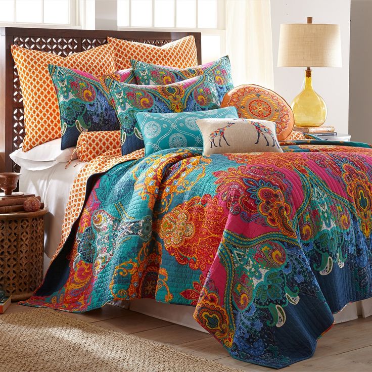 a bed with colorful comforters and pillows in a room