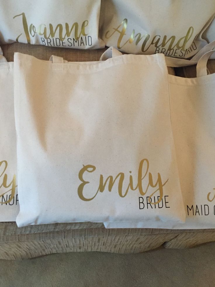 four bridesmaid tote bags sitting on top of a couch with gold lettering