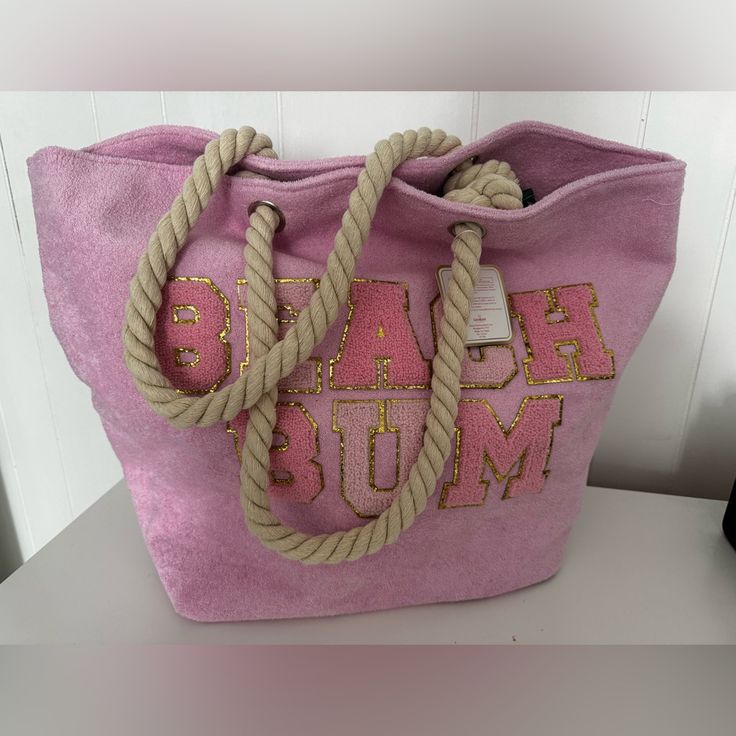 a pink bag with rope handles and letters on the front is sitting on a table