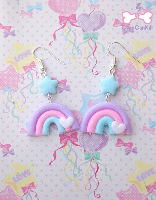 a pair of earrings with rainbows and stars hanging from them on a pink background