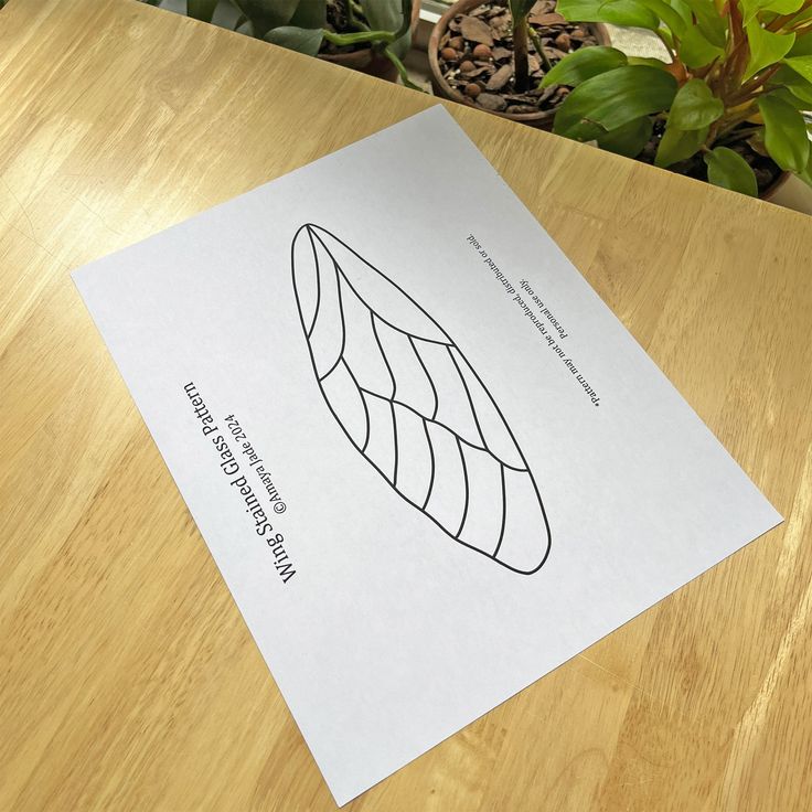 a piece of paper sitting on top of a wooden table next to a potted plant