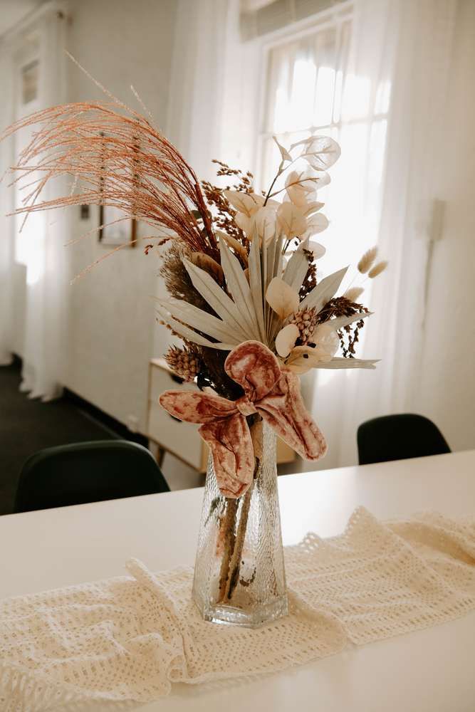 a vase filled with lots of flowers on top of a white table covered in lace