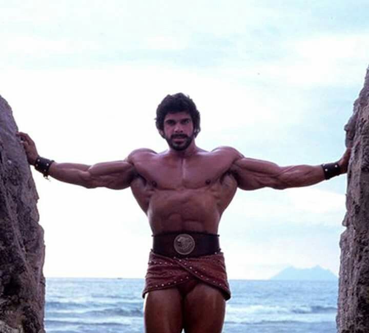 a man standing in between two large rocks on the beach with his arms stretched out