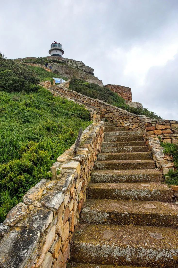 stone steps leading up to a light house on top of a hill