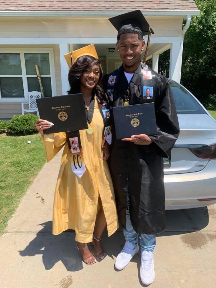 two people standing in front of a car holding diplomas