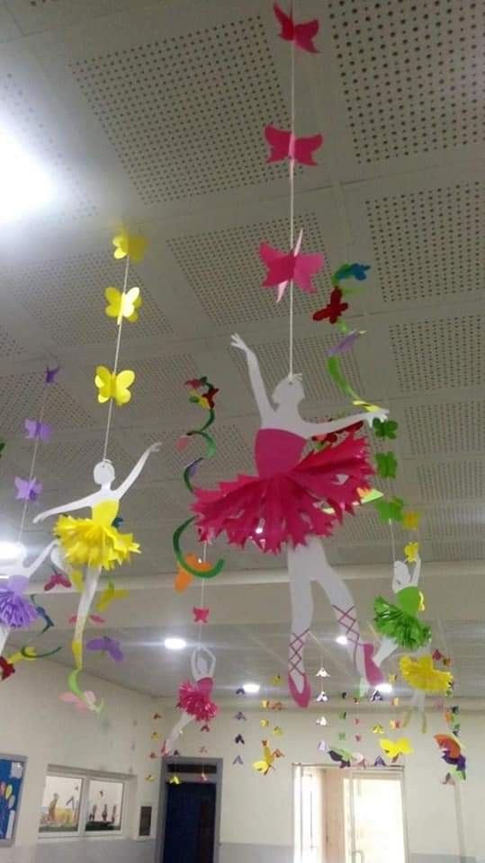 some paper butterflies hanging from the ceiling in a school room with a ballerina on it