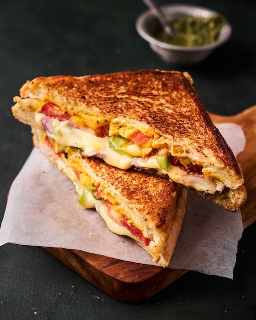 a grilled cheese sandwich sitting on top of a wooden cutting board