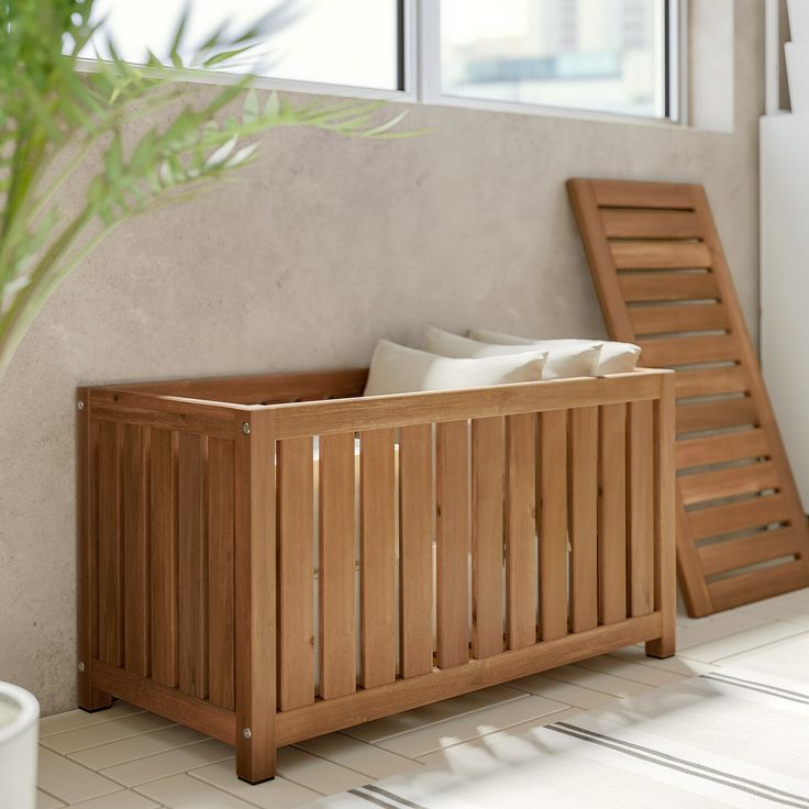 a wooden bench sitting in front of a window next to a potted green plant