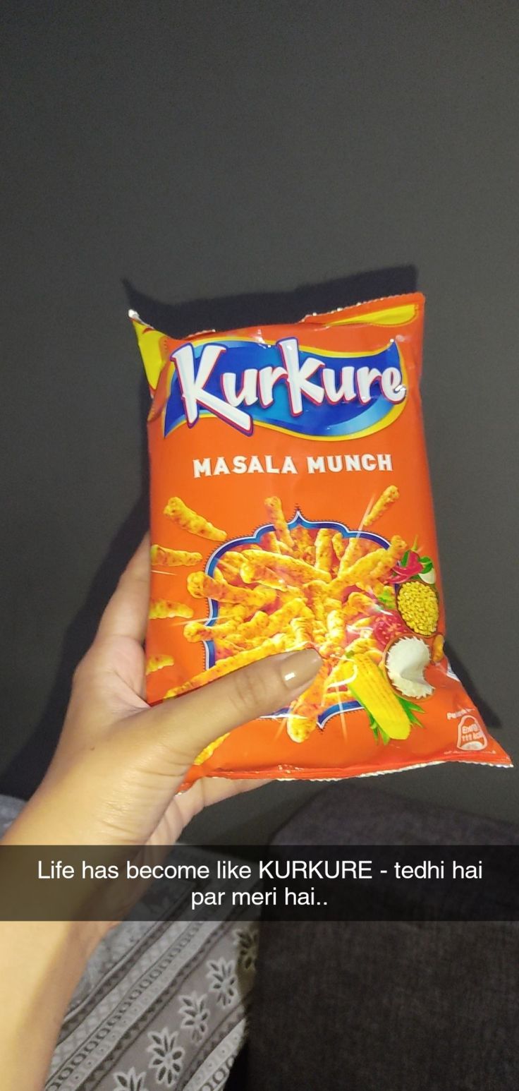 a person holding up a bag of kurkure masala munchi chips