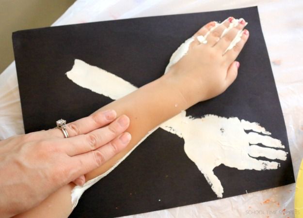 a child's hand is being held up by an adult with white paint on it