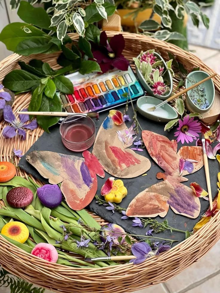 a basket filled with lots of different types of flowers and paints on top of it