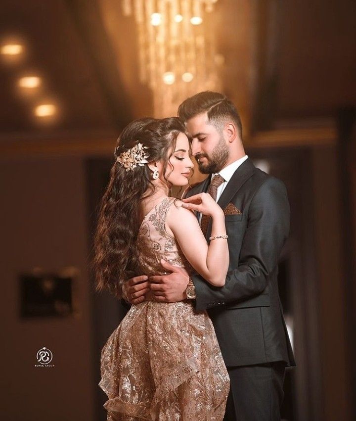 a bride and groom embracing each other in front of a chandelier