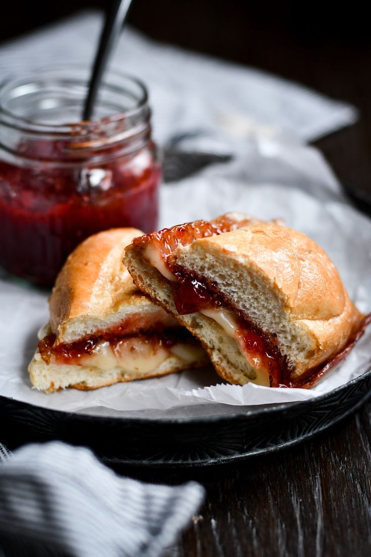 a sandwich cut in half sitting on top of a white plate next to a jar of jelly