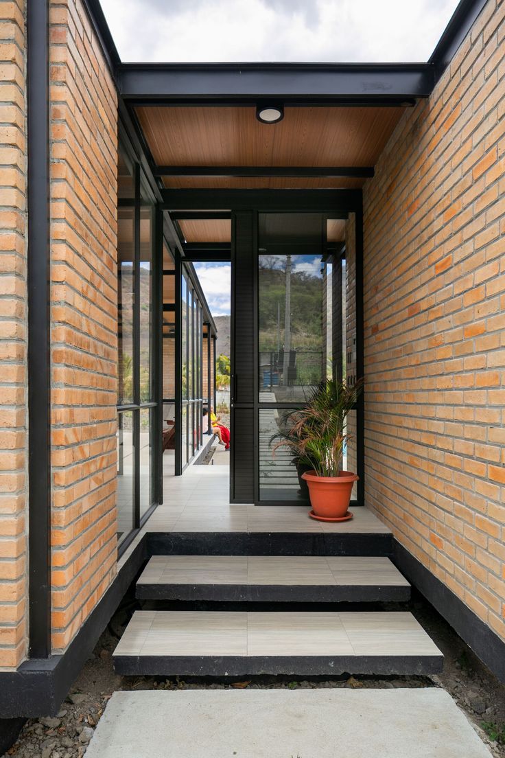 an entry way with steps leading up to the front door and potted plants on either side