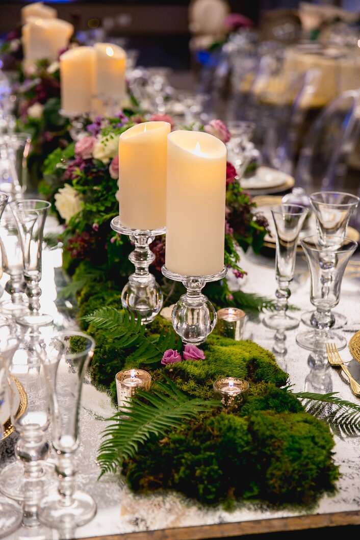 the table is set with candles and greenery