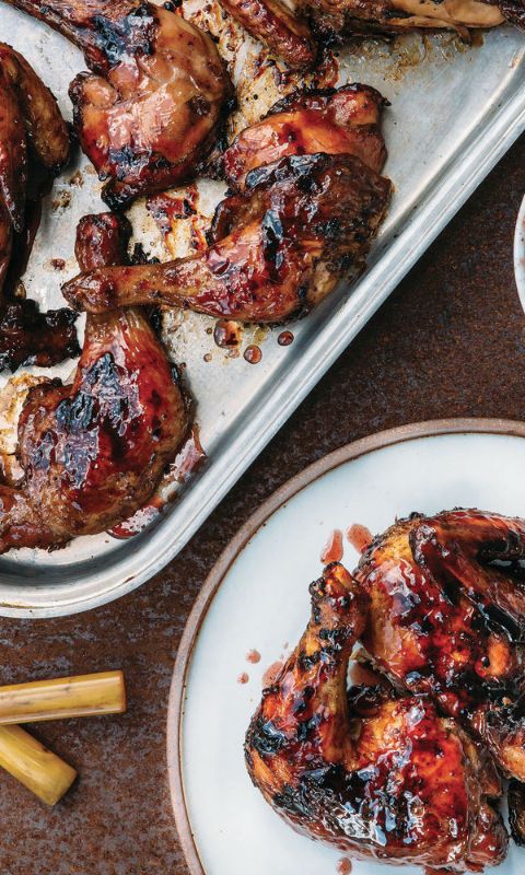 two plates with food on them next to a pan filled with chicken wings and sauces