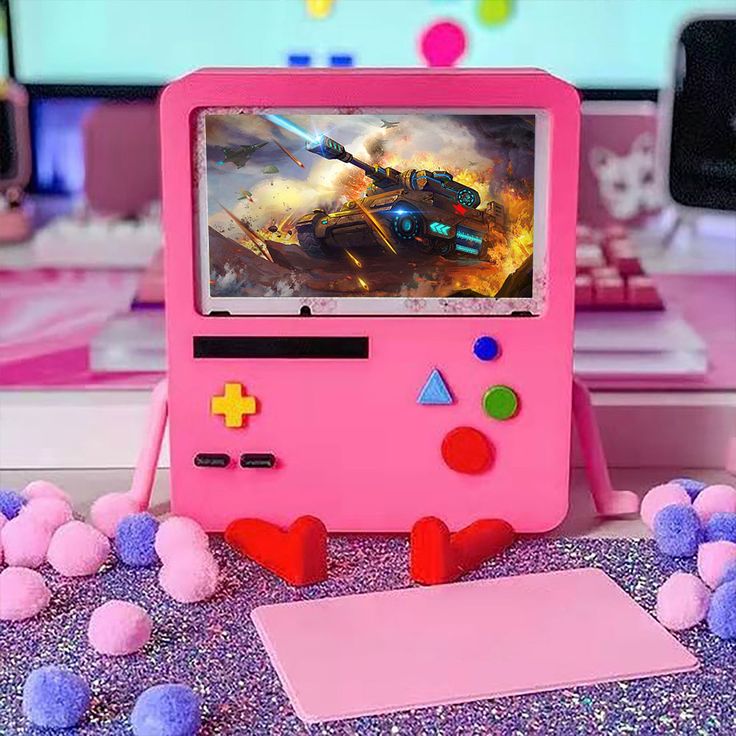 a pink video game console sitting on top of a table with pom poms around it