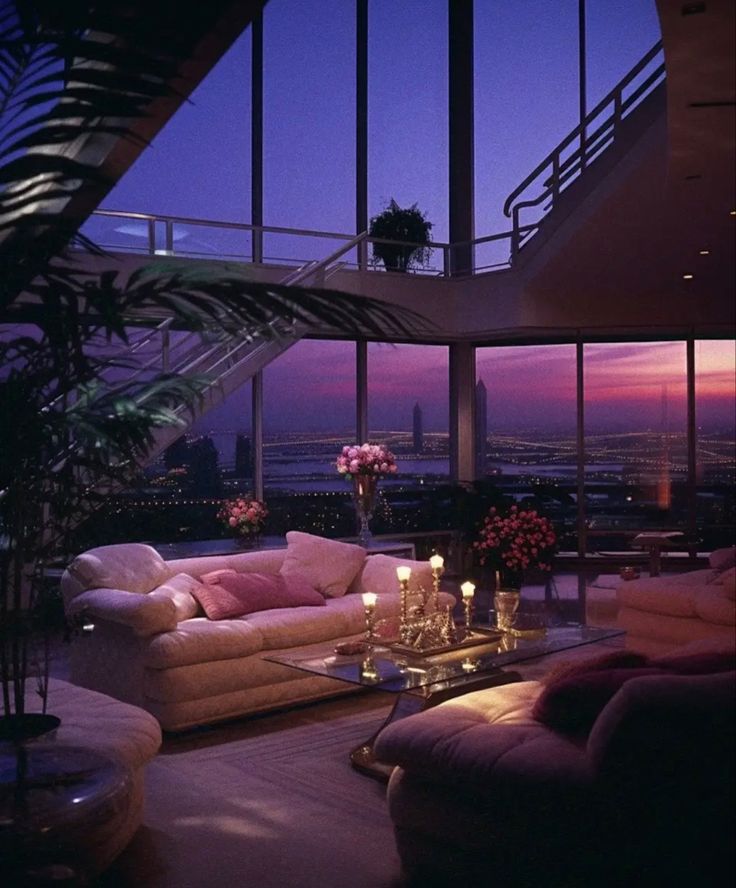 a living room filled with lots of furniture and large windows overlooking the city at night