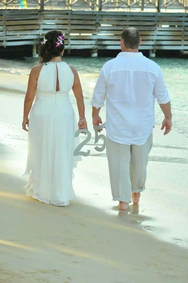 a man and woman walking on the beach holding hands