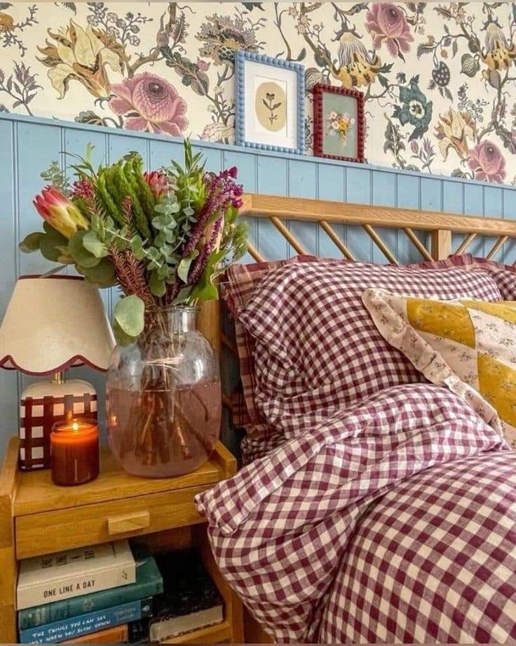 a vase with flowers on a nightstand next to a bed