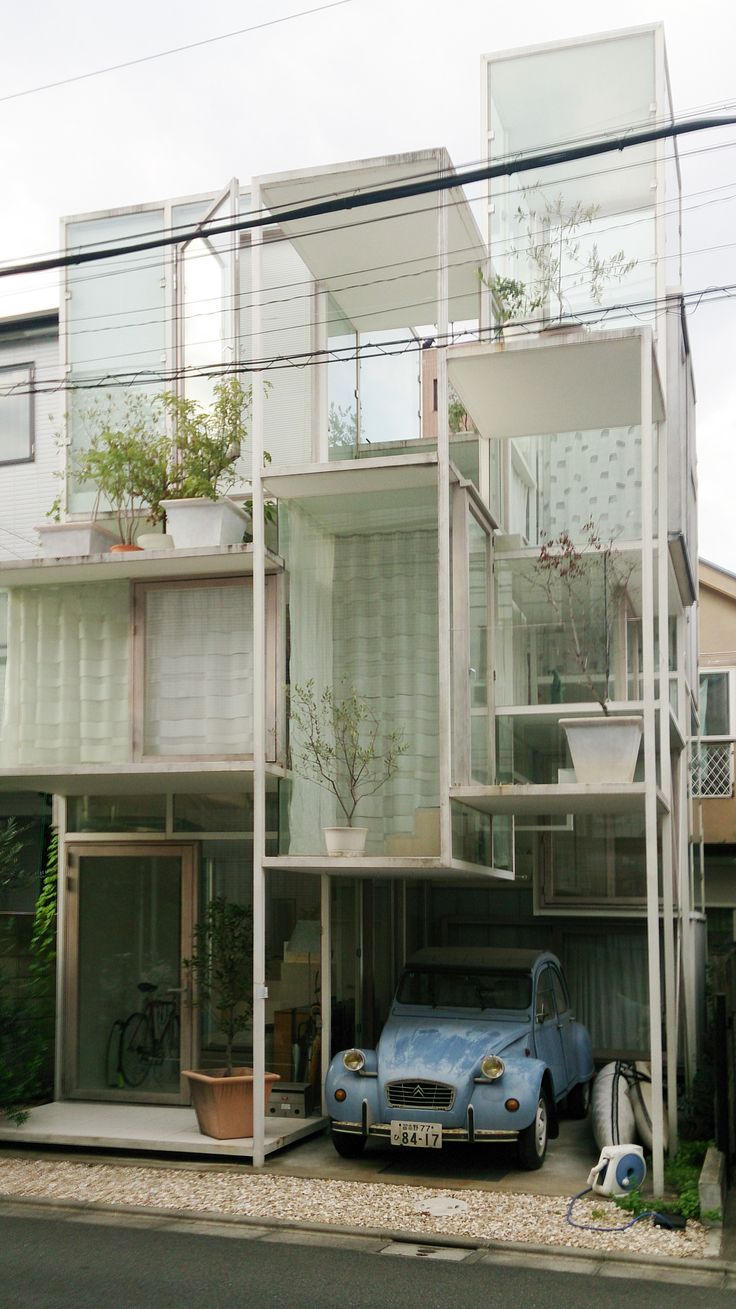 a car is parked in front of a house with glass balconies on the roof