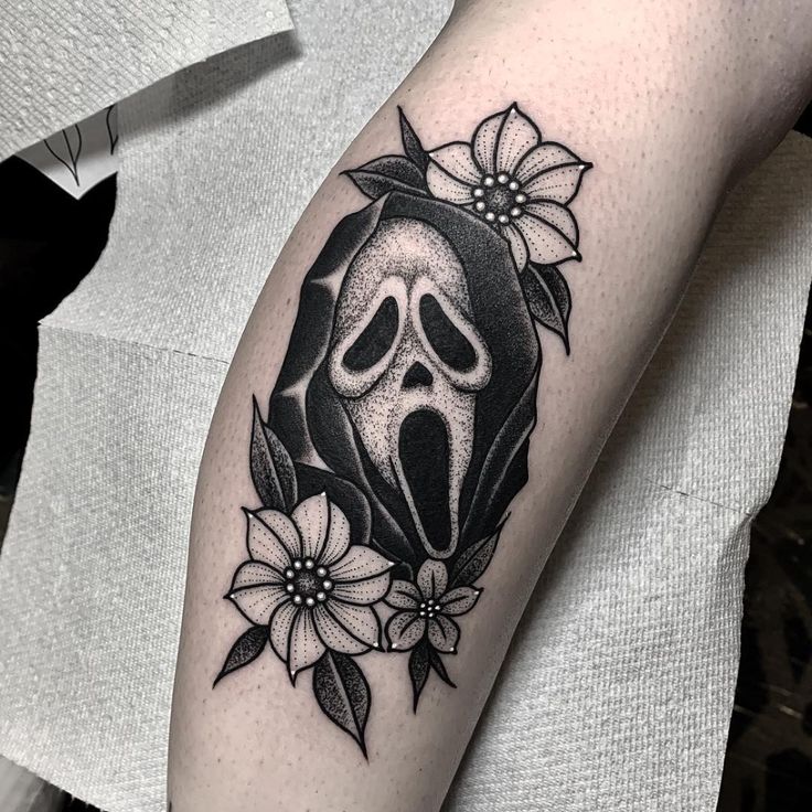 a black and white image of a skull with flowers on it's arm,