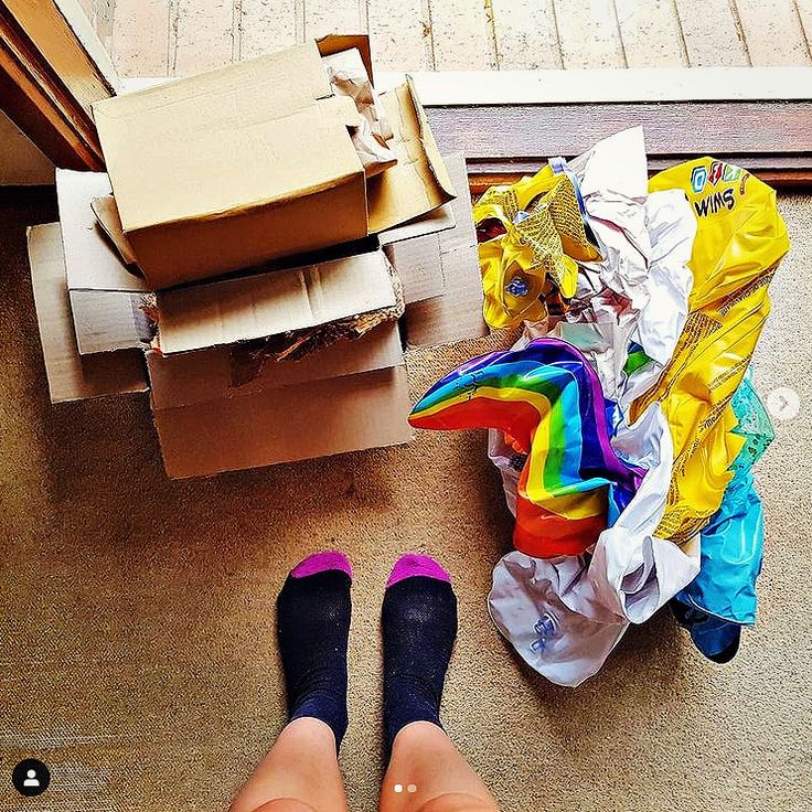 two people standing in front of boxes and bags on the floor with their feet up