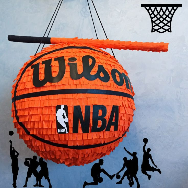 an orange basketball hanging from the side of a wall with people silhouettes around it