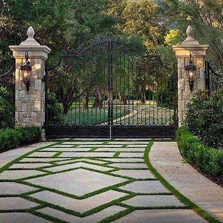 an entrance to a home with stone walkway and iron gates, surrounded by greenery