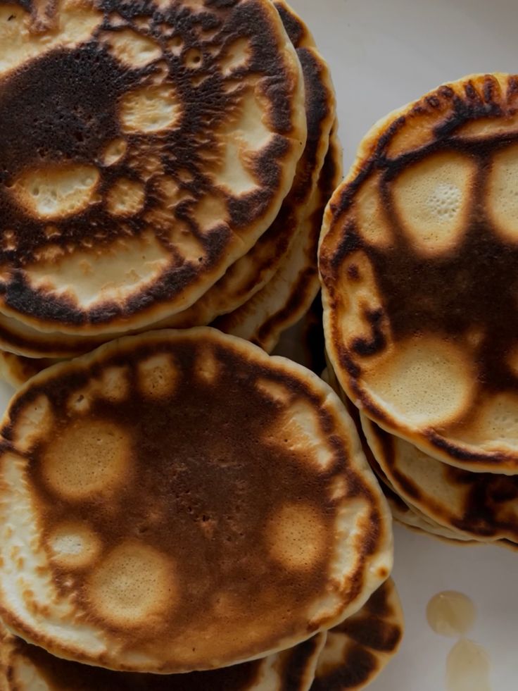 four pancakes on a white plate with brown spots